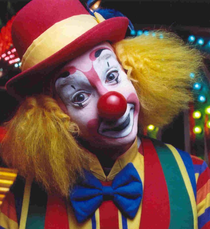 a close up of a clown wearing a red hat