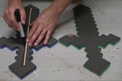 a person is using a stick to cut out paper shapes with chopsticks on the floor