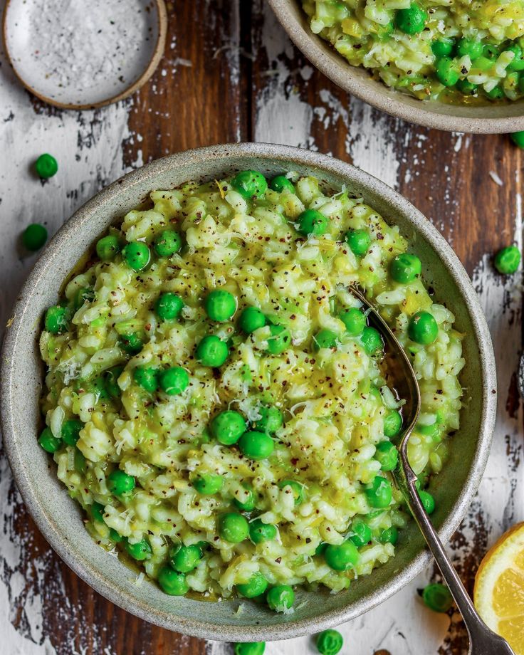 two bowls filled with rice and peas on top of a wooden table next to sliced lemons