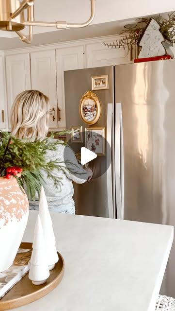 a woman is standing in front of a refrigerator with christmas decorations on the counter top