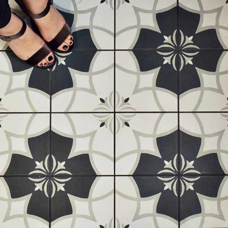 a person standing on a tiled floor with black and white tiles in the shape of flowers