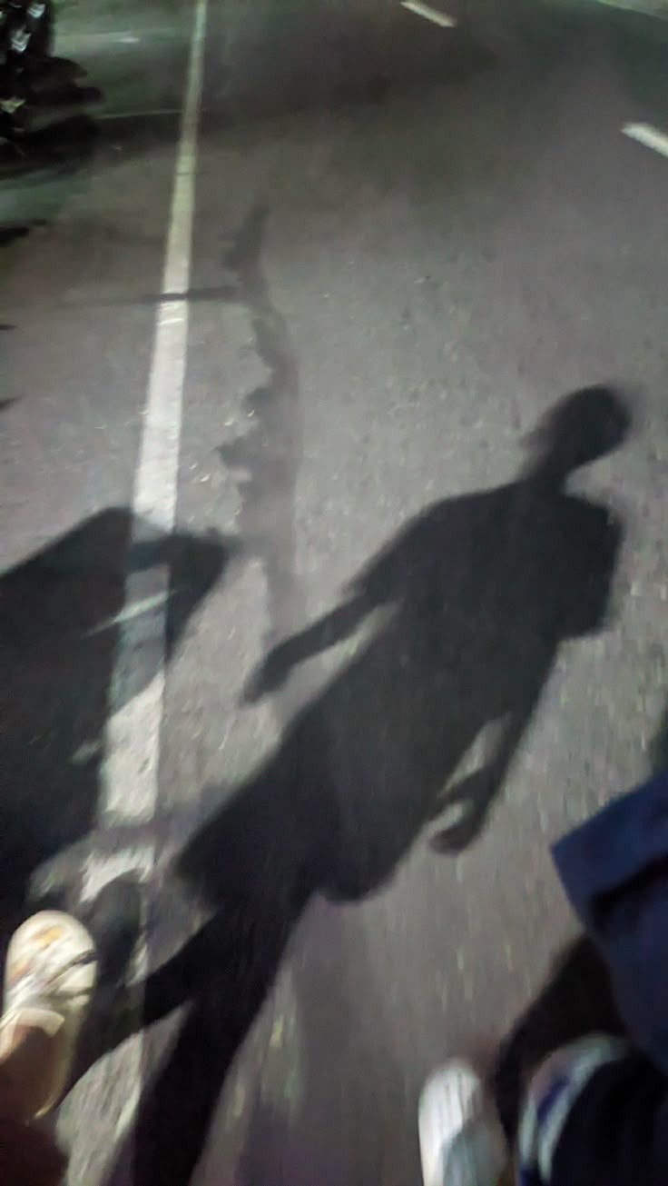 the shadow of two people riding motorcycles on a street with other motorcyclists