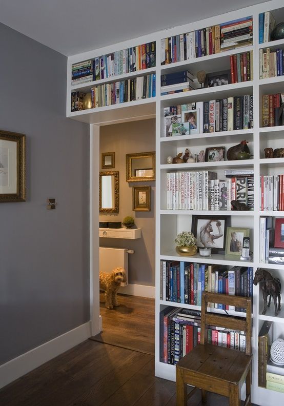 a bookshelf filled with lots of books next to a wooden table and chair