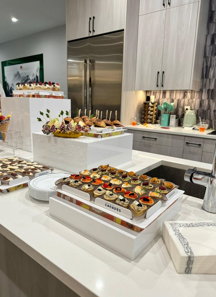 a kitchen counter with several trays of food on it