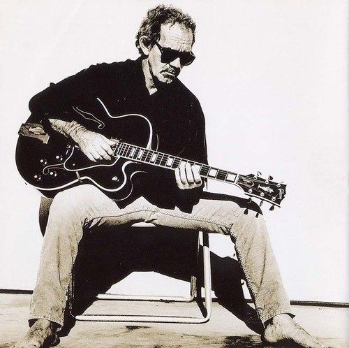 a black and white photo of a man playing an electric guitar