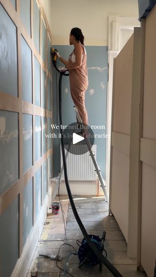 a woman is using a vacuum to clean the walls