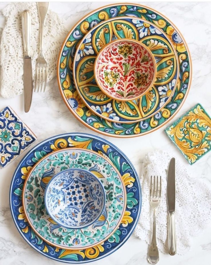 colorful plates and utensils laid out on a marble table top with lace napkins