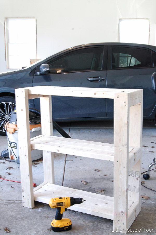 a car is parked in the garage behind a work bench made out of pallets