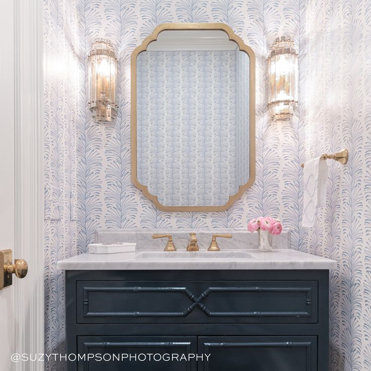 a bathroom vanity with a mirror above it and two lights on the wall next to it