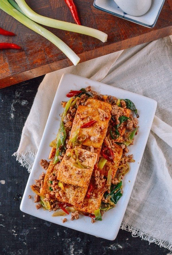 a white plate topped with tofu and veggies on top of a table