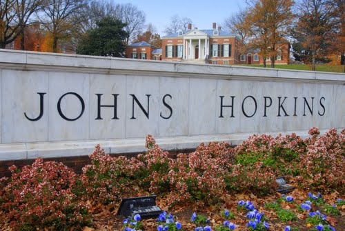 the john's hopkins sign is surrounded by flowers and shrubs in front of a brick building