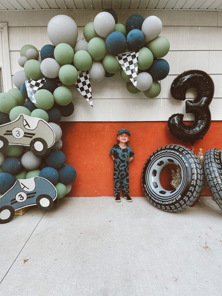 a boy standing in front of some tires and balloons