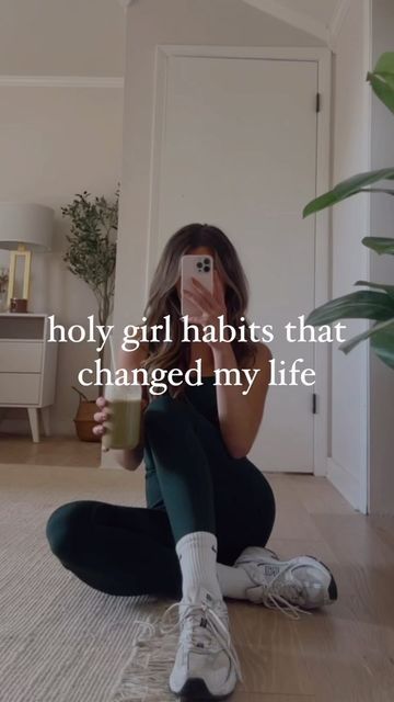 a woman sitting on the floor taking a selfie with her cell phone and holding a cup