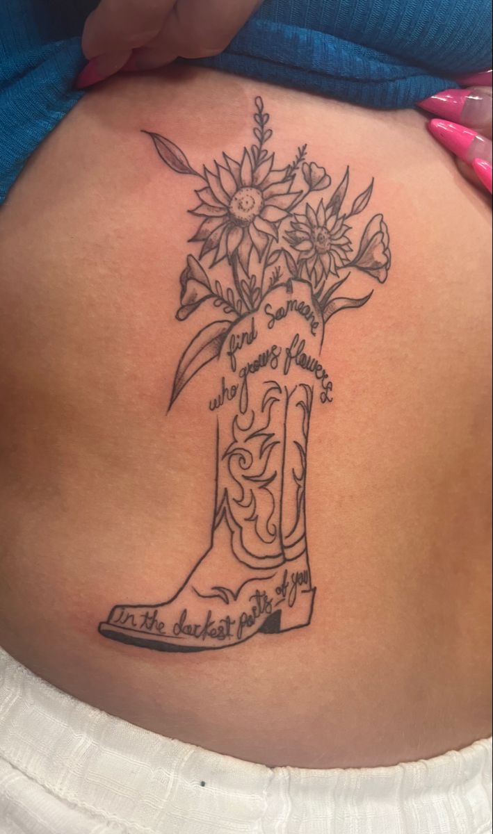 a woman's stomach with a boot and flowers tattoo on the side of her belly