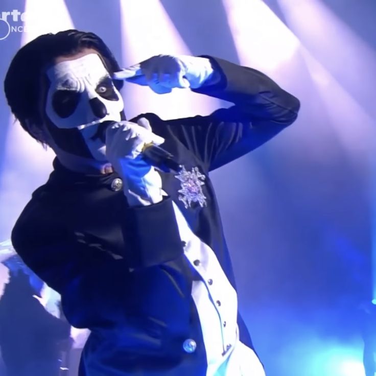 a man with white face paint on his face and holding a microphone in front of him