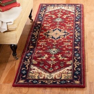 a red and blue rug on the floor next to a table with books in it