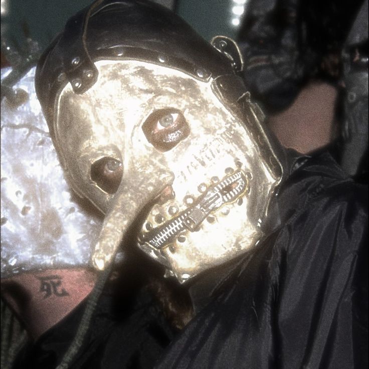 a person wearing a gold mask and black jacket