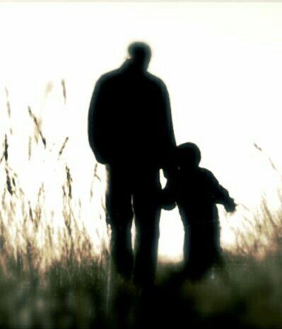 the silhouette of a man and child walking through tall grass