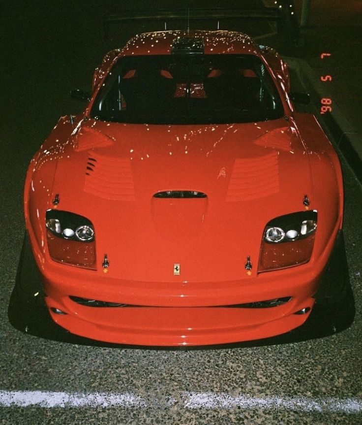 a red sports car is parked on the side of the road at night with its hood up