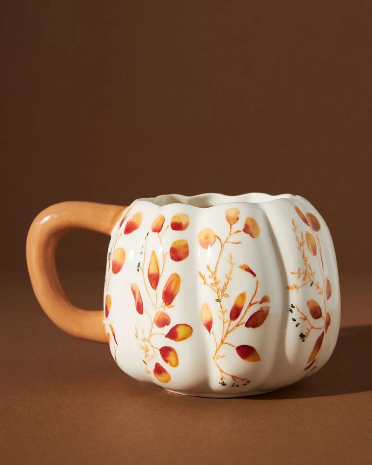 a ceramic mug with an orange handle on a brown surface, sitting in front of a brown background