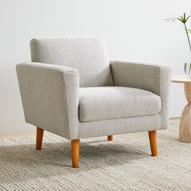 a white chair sitting on top of a rug next to a vase filled with flowers