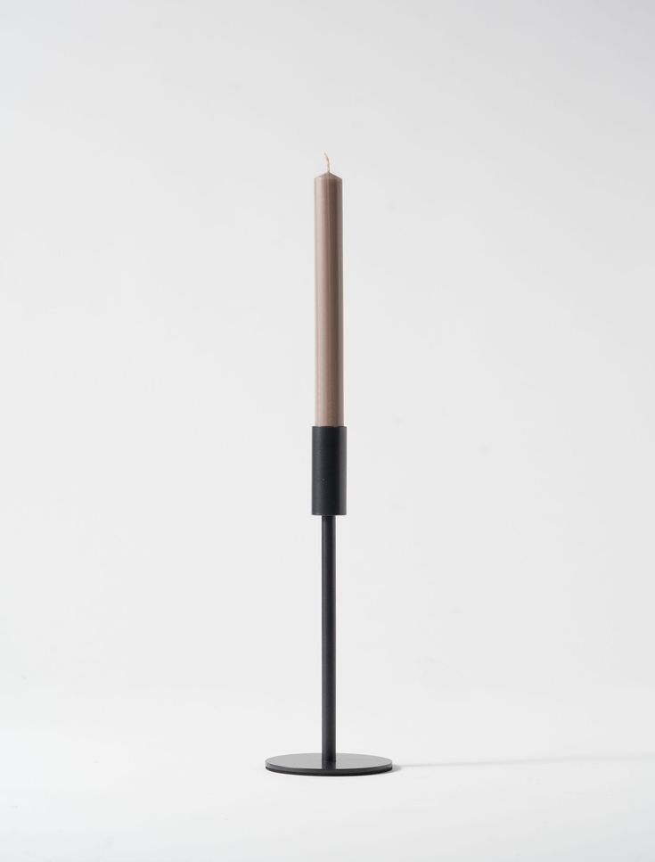 a single candle sitting on top of a black stand