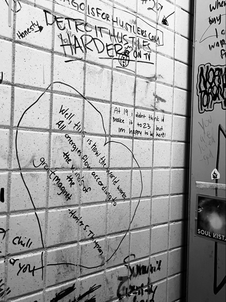 the bathroom wall is covered in graffiti and has many writing on it, including words