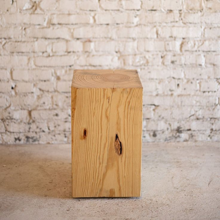 a wooden block sitting on top of a floor next to a white brick wall with a small hole in it