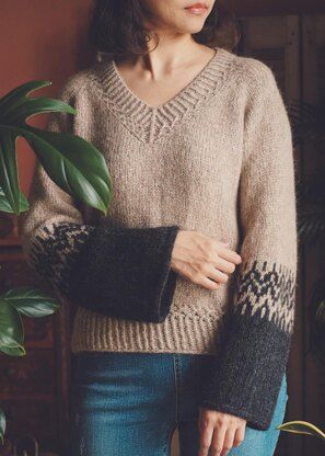 a woman standing next to a potted plant wearing a sweater with an argyle pattern