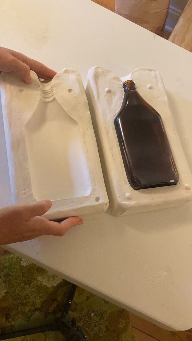 two empty trays on a table with one holding a bottle and the other holding a plastic container