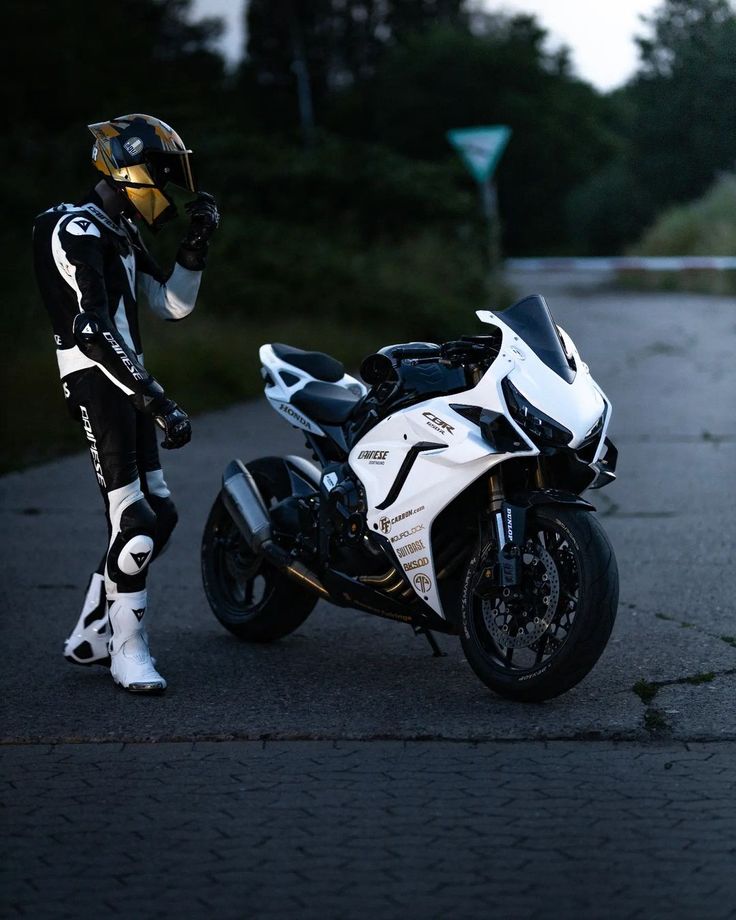 a person dressed in black and white standing next to a motorcycle