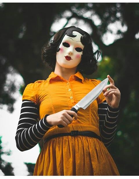 a woman wearing a mask and holding a knife