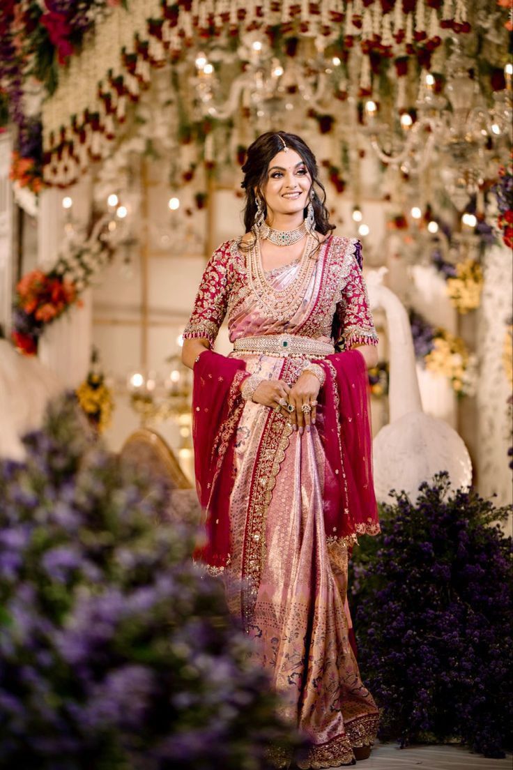 a woman in a red and gold sari is standing under a chandelier