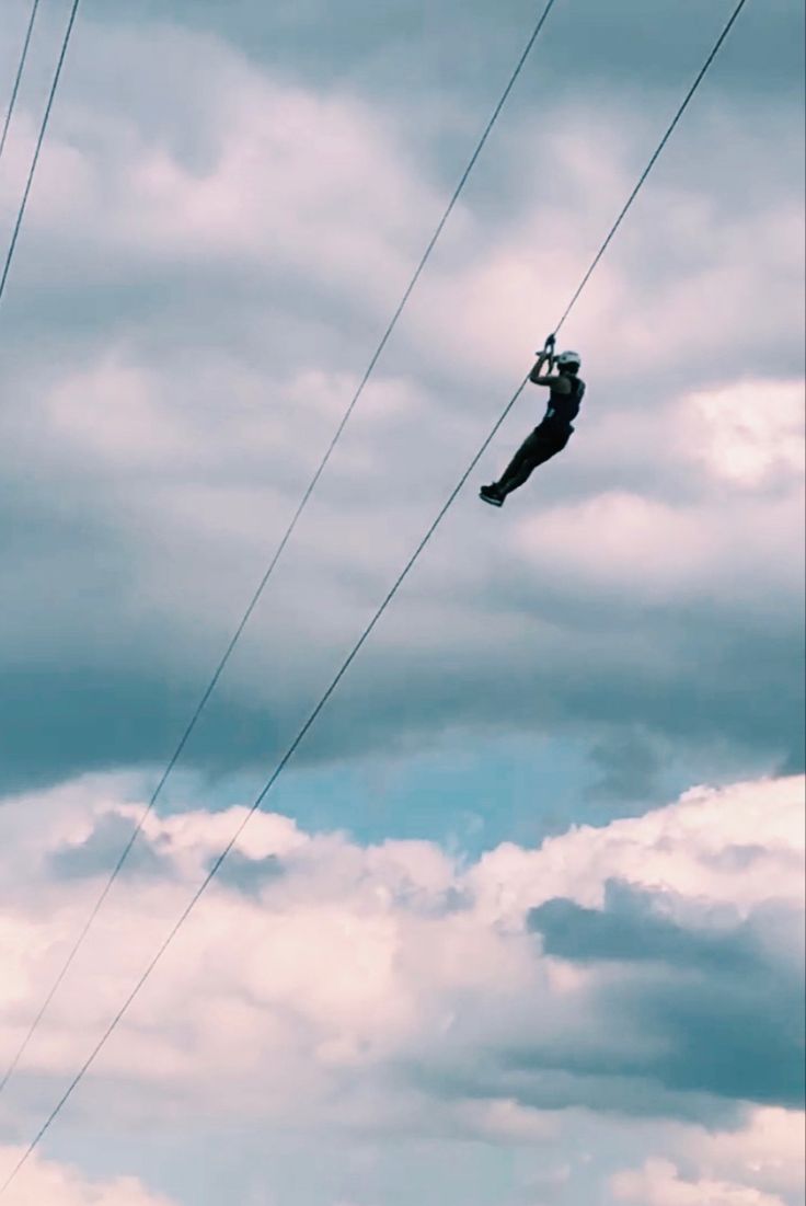 a person hanging on to some wires in the sky