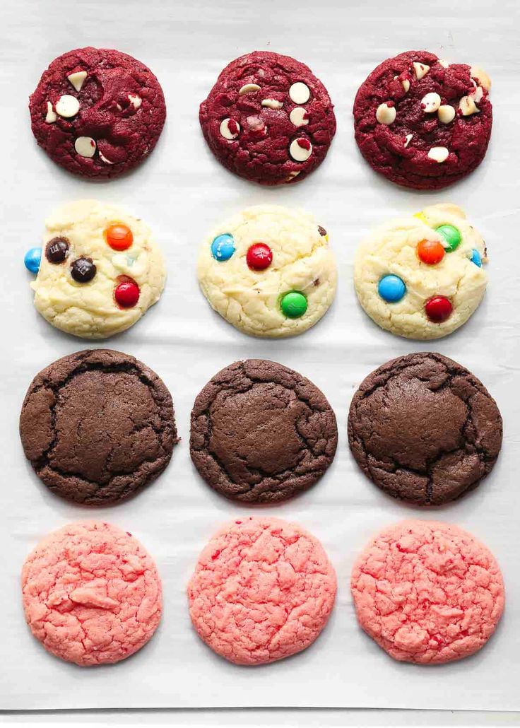 cookies and chocolates are arranged on a sheet of parchment paper, including one cookie with candy eyes