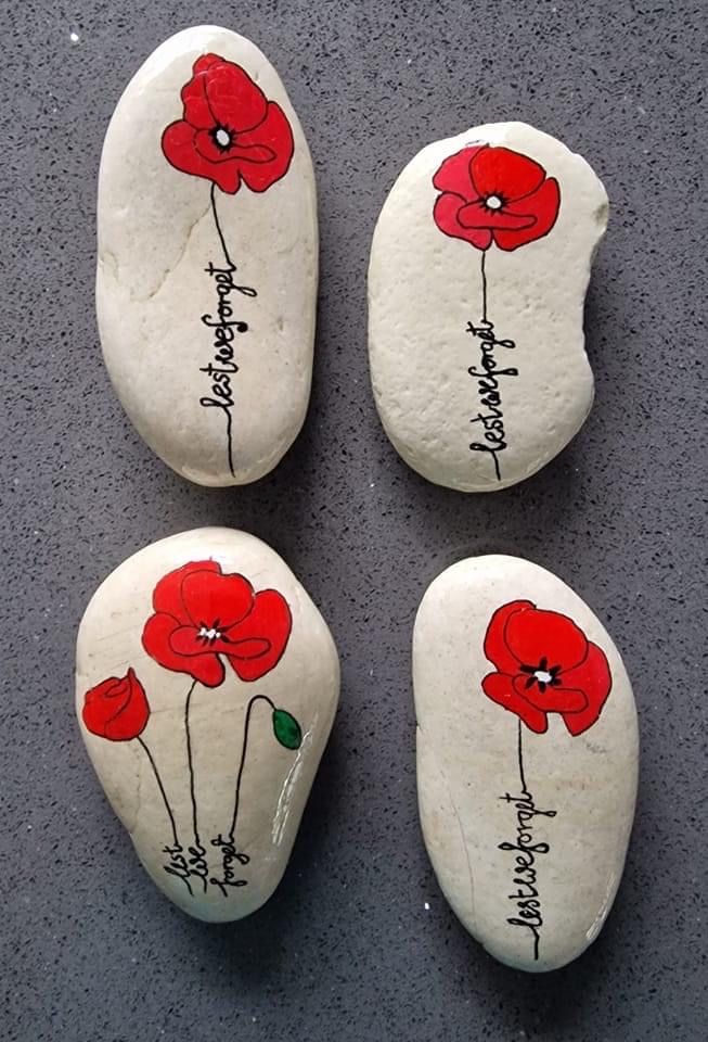 four red flowers painted on white rocks with black writing that read, happy birthday and have names written on them