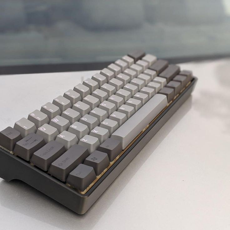 a computer keyboard sitting on top of a white table next to a window with cars in the background