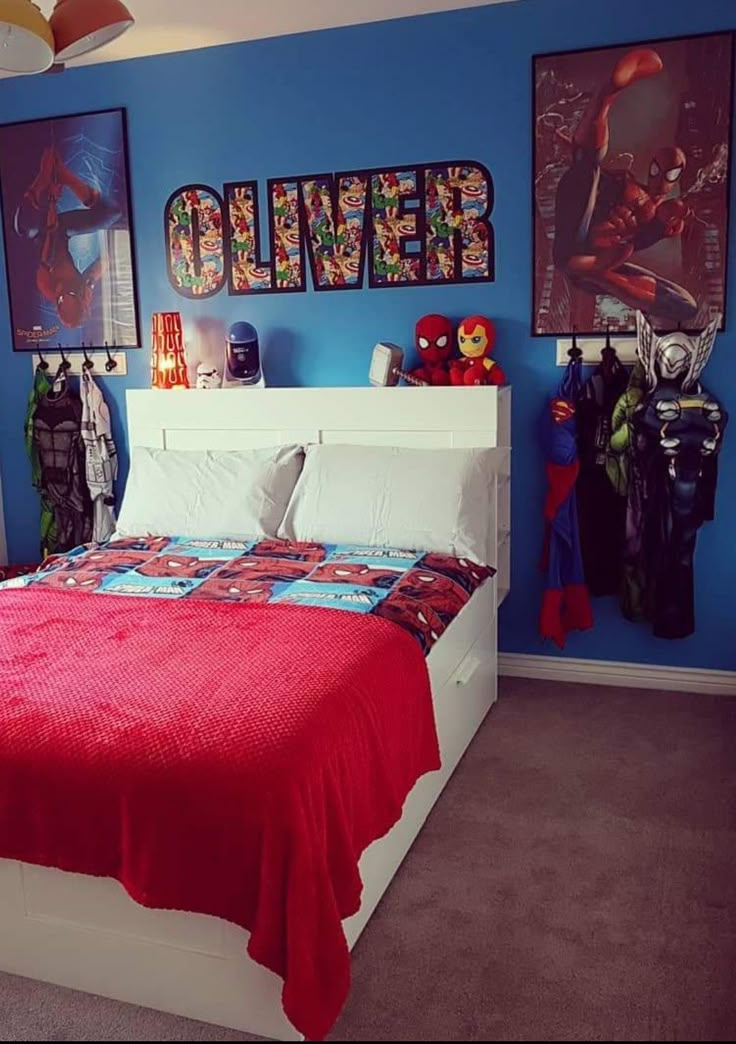 a bedroom decorated in blue and red with spiderman pictures on the wall above the bed