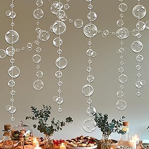 the table is set with plates, cups and vases on it as well as bubbles hanging from the ceiling