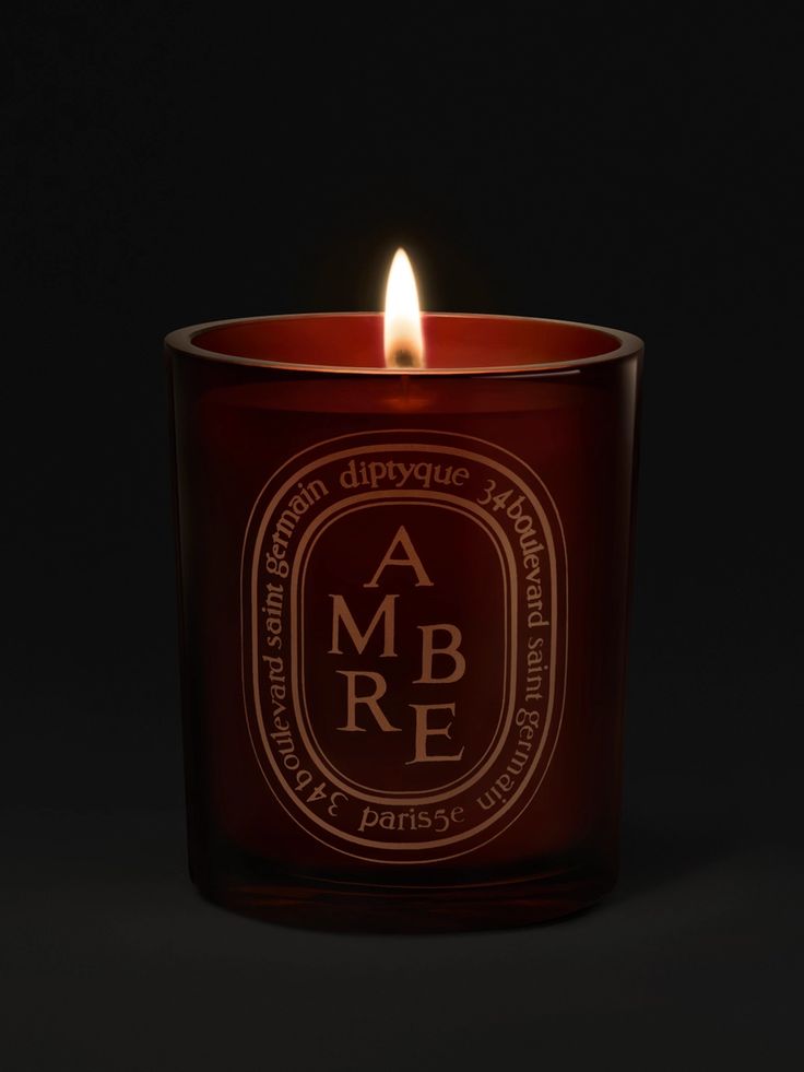 a candle that is lit in the dark with an ambre logo on it's side