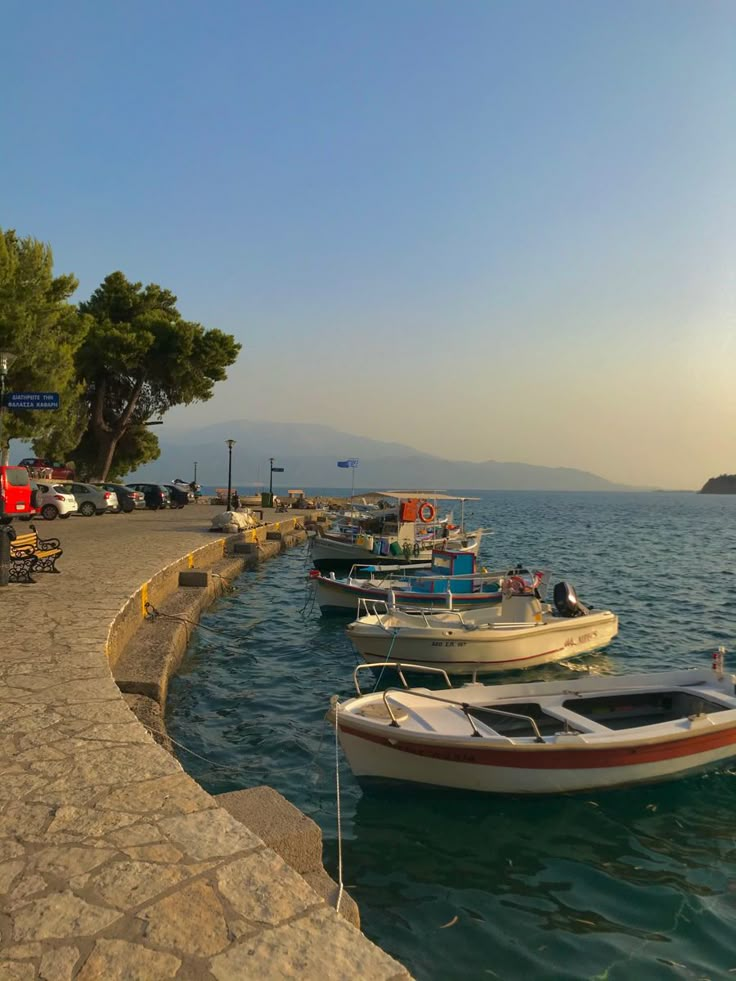 there are many boats that are docked in the water by the shore line at sunset