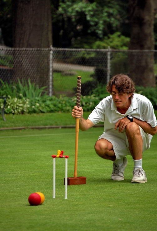 a man squatting down to pick up a ball with a bat on the ground