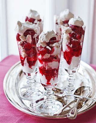 three glasses filled with dessert sitting on top of a silver tray next to a pink table cloth