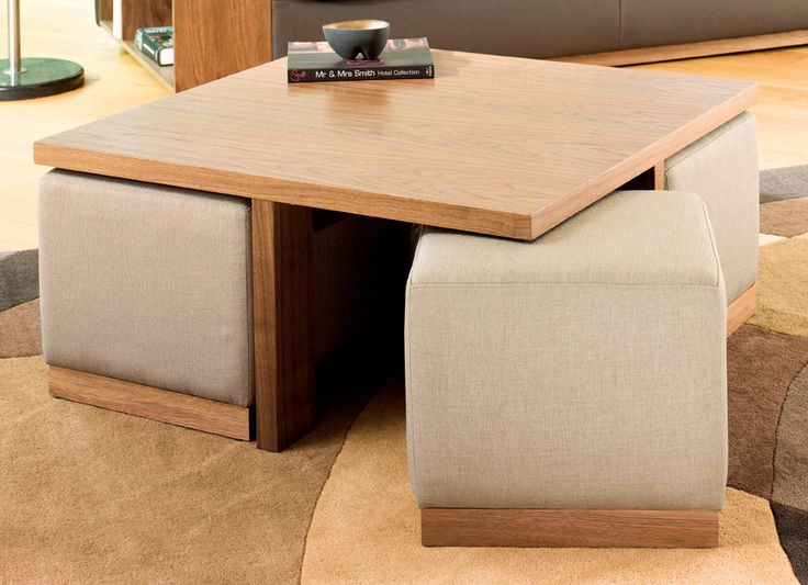 a coffee table with two stools and a book on it in a living room