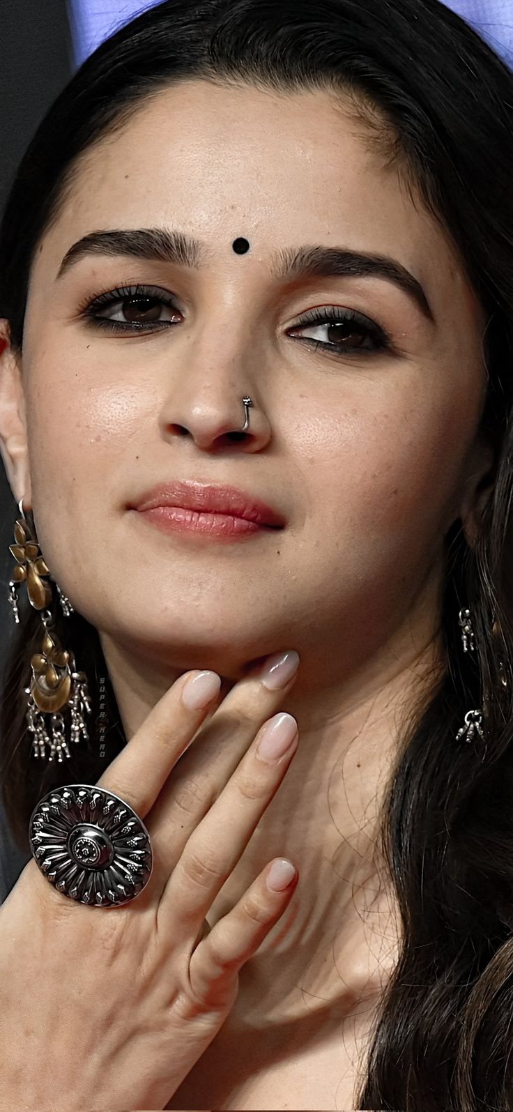 a close up of a person wearing large earrings and holding her hand near her face