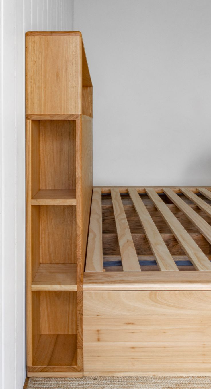 a wooden bed frame and book shelf in a room