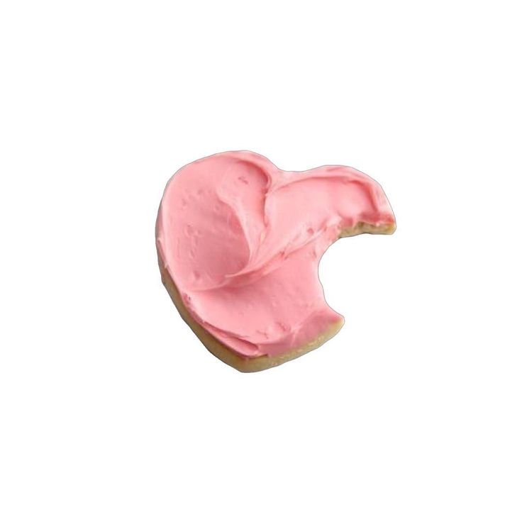 a pink frosted heart shaped cookie with icing on it's side against a white background