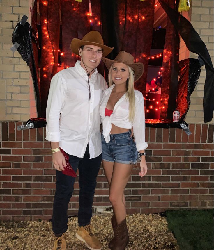 a man and woman standing next to each other in front of a brick wall with lights