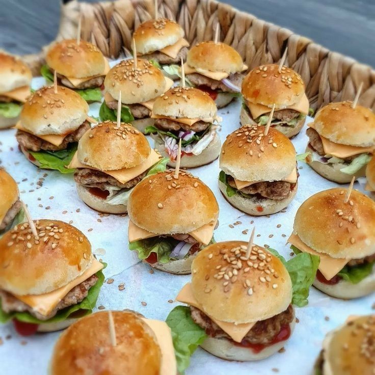 mini hamburgers with toothpicks on them sitting in a basket