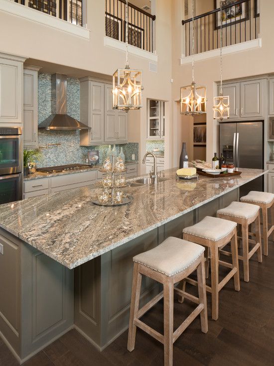 a large kitchen with an island and marble counter tops in front of stainless steel appliances